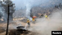 Para petugas pemadam kebakaran memadamkan titik-titik api kebakaran hutan di Hutan Nasional Los Angeles, California, 13 Agustus 2020.