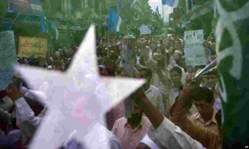 Supporters of a Pakistani religious group Jamaat-e-Islami chant slogans as they seen through their party flag during an anti American rally in Abbottabad, Pakistan, May 6, 2011 (AP).