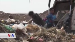 کچێکی منداڵ بە جلوبەرگی پـیاوانە خاشاک بۆ بژێوی ژیانی کۆدەکاتەوە