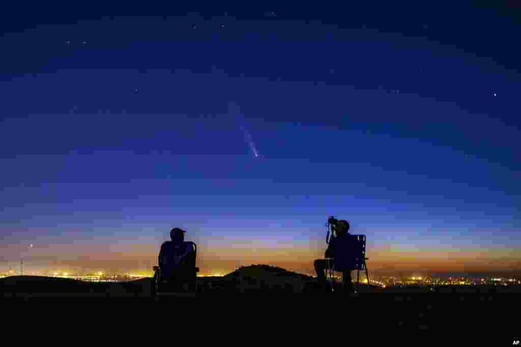 Komet Tsuchinshan-Atlas muncul di langit malam barat saat fotografer amatir Nolan Letellier, kiri, dan Link Jackson mengamati di bukit dekat Dry Creek Trailhead di Boise, Idaho. (AP)&nbsp;