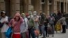 People line up as they wait to receive a ration of donated food by volunteers of the Santa Ana church in Barcelona, Spain, May 14, 2020. 