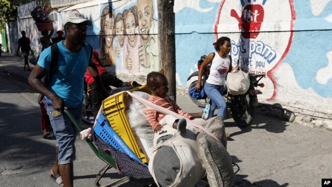 Sejumlah warga meninggalkan rumah mereka saat bentrokan antara polisi dan anggota geng, di Port-au-Prince, Haiti, Sabtu, 9 Maret 2024. (Foto: Odelyn Joseph/AP Photo)