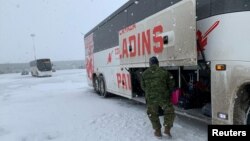 加拿大空军从中国撤侨的飞机抵达安大略的一个空军基地后，士兵把侨民的行李装上大巴车。（2020年2月7日）