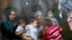 Syrian refugees look through a window inside a refugee centre as they wait for a distribution of humanitarian aid by volunteers of the Bulgarian Red Cross in Sofia.