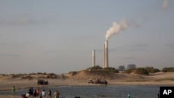 FILE - Israel's electricity power plant in Ashkelon is seen as people bath near kibbutz Zikim, on the Israel Gaza Border, June 19, 2017. 