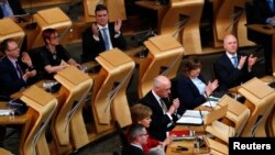 Anggota parlemen dari Partai Nasional Skotlandia bertepuk tangan setelah melaksanan pemungutan suara untuk referendum kemerdekaan yang kedua di Gedung Parlemen di Holyrood, Edinburgh, 28 Maret 2017 (foto: REUTERS/Russell Cheyne)