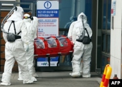 Medical workers wearing protective gear carry a patient infected with the COVID-19 coronavirus at a hospital in Chuncheon, Feb. 22, 2020.