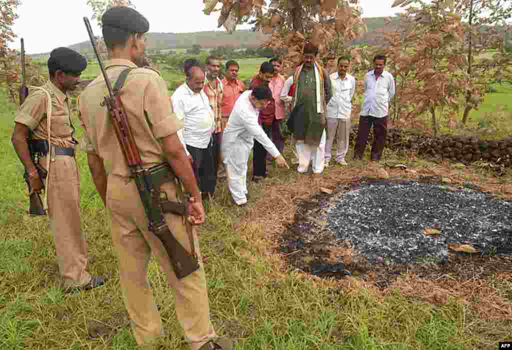 Dân làng trong bang Madhya Pradesh, Ấn Độ đứng xung quanh chỗ tự thiêu ngày hôm trước của bà Janak Rani, muốn chết theo chồng, khi ông qua đời và được hỏa táng. Tục lệ này đã bị ngăn cấm từ lâu tại Ấn Độ. 22 tháng 8, 2006. (AP)