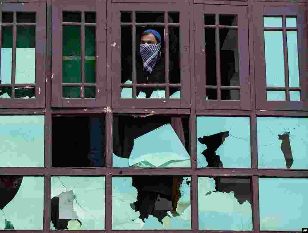 A Kashmiri man watches from a damaged house during a gun battle between government forces and suspected rebels on the outskirts of Srinagar, Indian-controlled Kashmir.