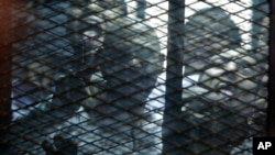 FILE - Egyptian activists are seen through the mesh of a courtroom cage in Cairo, Egypt, Feb. 23, 2015. 