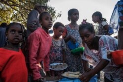 Displaced children from Western Tigray gather at meal time to receive food outside a classroom in the school where they are sheltering in Tigray's capital Mekele, Ethiopia, Feb. 24, 2021.
