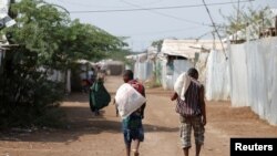 FILE - Men carry bags of food aid at the Kakuma refugee camp in northern Kenya, March 6, 2018. 