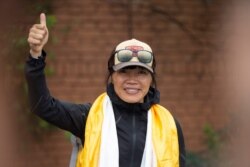 Tsang Yin-hung, 45, of Hong Kong who scaled Mount Everest from the base camp in 25 hours and 50 minutes, and became the fastest female climber gestures to media as she arrives in Kathmandu, Nepal, May 30, 2021.