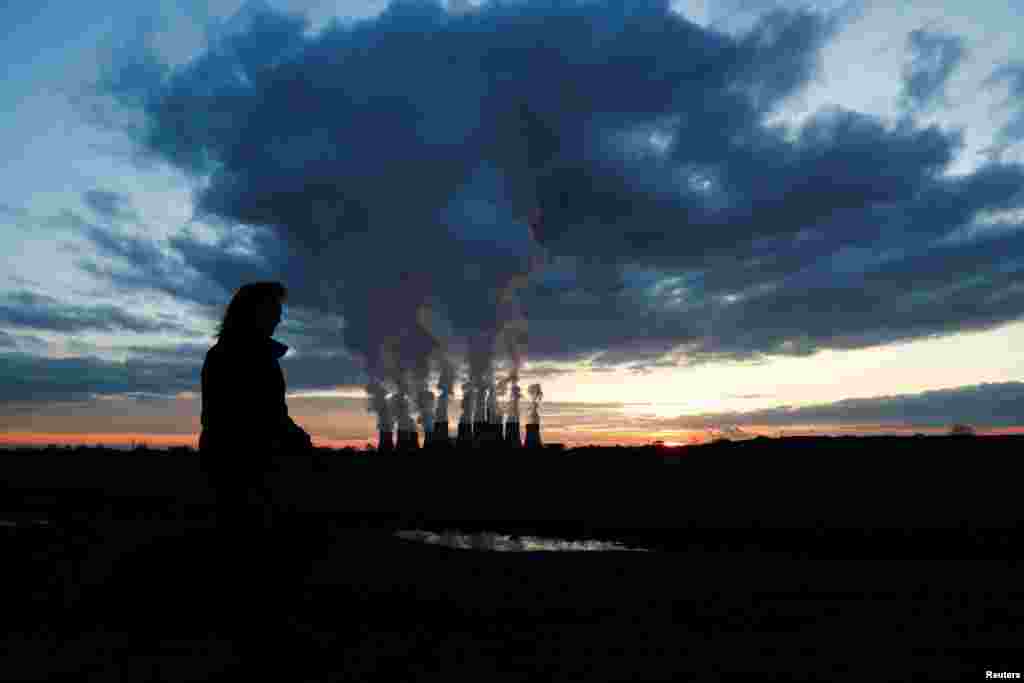 A woman walks a dog past Drax power station during the sunset in Drax, North Yorkshire, Britain, Nov. 27, 2020.