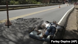 Venezuelan migrants sleep on a mattress on the side of the highway in Pamplona, Colombia, Wednesday, Oct. 7, 2020,(AP Photo/Ferley Ospina)