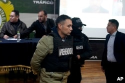Miguel Angel Burgos dalam keadaan diborgol oleh polisi muncul saat konferensi pers setelah penangkapannya di La Paz, Bolivia, Jumat, 28 Juni 2024. (Foto: AP)