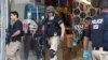 Law enforcement agents leave a clothing store after a raid in the Los Angeles Fashion District Wednesday, Sept. 10, 2014.