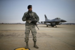 FILE - A U.S. soldier stands guard in front of their Air F-16 fighter jet at Osan Air Base in Pyeongtaek, South Korea, Jan. 10, 2016.