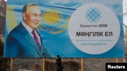 A woman walks past a poster depicting Kazakhstan's President Nursultan Nazarbayev in Almaty, Feb. 16, 2015.