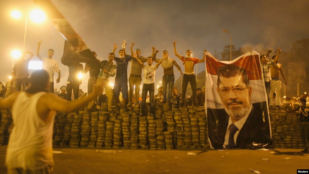 Para pendukung presiden Mesir terguling, Mohamed Morsi, berdiri berjajar di barikade yang mereka dirikan untuk memisahkan diri dari kora Nasr, timur Kairo (27/7). Demonstran pro-Morsi terus melanjutkan aksi mereka, mengabaikan perintah militer untuk segera membubarkan diri dan mengakhiri aksi duduk.