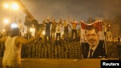 Para pendukung presiden Mesir terguling, Mohamed Morsi, berdiri berjajar di barikade yang mereka dirikan untuk memisahkan diri dari kora Nasr, timur Kairo (27/7). Demonstran pro-Morsi terus melanjutkan aksi mereka, mengabaikan perintah militer untuk segera membubarkan diri dan mengakhiri aksi duduk.