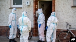 Members of German Red Cross (DRK) stand in front of a house where employees of the Toennies meat factory live in Rheda-Wiedenbrueck, Germany. Hundreds of new coronavirus cases are linked to the large meatpacking plant, June 22, 2020.