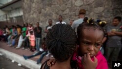 FILE - A Haitian woman carries her daughter as she waits outside the Mexican Commission for Migrant Assistance office in Tapachula, early Thursday, June 20, 2019. Migrants, mostly from Haiti, have burst Sept. 18, 2023, into an asylum office in Tapachula, to demand papers.