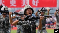 FILE - In this June 30, 2019, file photo, soldiers of Chinese People's Liberation Army demonstrate their skill during an open day of Stonecutter Island naval base, in Hong Kong. China is revising its National Defense Education Law to expand military training.