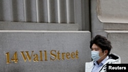 A person wearing a face mask walks along Wall Street after further cases of coronavirus were confirmed in New York City, New York, U.S., March 6, 2020. REUTERS/Andrew Kelly