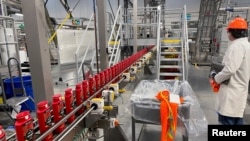 FILE - A person works with robots at Procter & Gamble's factory in Tabler Station, West Virginia, U.S., May 28, 2021. 