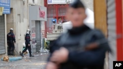 Firemen, left, leave building of Wednesday's raid on apartment in Paris suburb Saint-Denis, Nov.19, 2015. 