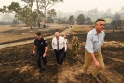 FILE - Australian Prime Minister Scott Morrison, center, tours the Wildflower farm owned by Paul and Melissa Churchman in Sarsfield, Victoria, Jan. 3, 2020. Morrison is being criticized for the fire response, which is seen as slow and detached.