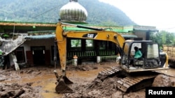 FILE - An excavator moves soil during the search and rescue of victims on the site of a landslide caused by heavy rain at Semangat Gunung Village in Karo, North Sumatra province, Indonesia, Nov. 25, 2024.