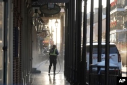 A man uses a power washer on Toulouse street a day after a vehicle was driven into a crowd on New Orleans' Canal and Bourbon streets, Jan. 2, 2025.