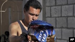 A man throws away blood stained items at a home in the northern city of Ciudad Juarez, Mexico, Saturday Oct. 23, 2010.