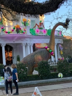 A festively-dressed dinosaurs greets visitors at this home in New Orleans. (Matt Haines/VOA)