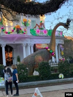 A festively-dressed dinosaurs greets visitors at this home in New Orleans. (Matt Haines/VOA)