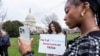 FILE - Devotees of TikTok, Mona Swain, center, and her sister, Rachel Swain, right, both of Atlanta, pose with a sign at the Capitol in Washington, March 13, 2024.