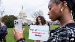 FILE - Devotees of TikTok, Mona Swain, center, and her sister, Rachel Swain, right, both of Atlanta, pose with a sign at the Capitol in Washington, March 13, 2024.