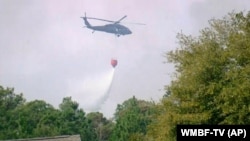 A helicopter drops water to help contain a fire in the Carolina Forest area west of the coastal resort city of Myrtle Beach, South Carolina, March 2, 2025, where residents were ordered to evacuate several neighborhoods. 