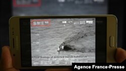 একজন পাকিস্তানি সাংবাদিক স্মার্টফোনে পাকিস্তানের নৌবাহিনী কর্তৃক প্রকাশিত একটি ভিডিও দেখছেন। পাকিস্তান নৌবাহিনী অভিযোগ করেছে যে একটি ভারতীয় সাবমেরিন পাকিস্তানের জলসীমায় প্রবেশের চেষ্টা করেছে। ৫ই মার্চ, ২০১৯। ছবি- এজেন্সি ফ্রান্স প্রেস 