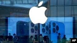 FILE - People check out the latest iPhone 13 handsets at an Apple Store in Beijing, China, Sept. 28, 2021. 