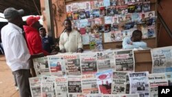 FILE - People look over local newspapers in Yaounde, Cameroon. Cameroon has suspended 16 journalists and seven news outlets for what it calls media offenses. 