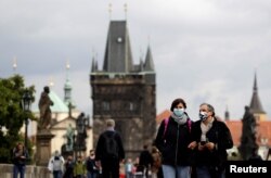 People wearing face masks walk across the medieval Charles Bridge as the spread of the coronavirus disease continues in Prague, Czech Republic, Sept. 25, 2020.