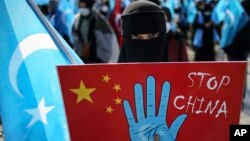 A protester from the Uyghur community living in Turkey holds up an anti-China placard during a protest against the visit of China's Foreign Minister Wang Yi to Turkey, in Istanbul, Thursday, March 25, 2021. (AP Photo/Emrah Gurel)