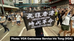 7月1日港版国安法实施第一日，数以万计香港人聚集在铜锣湾上街游行，有人高举被当局批评有港独含意的反送中运动旗帜（美国之音/汤惠芸）