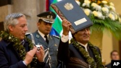 Bolivia's President Evo Morales, wearing garland made from coca leaves, holds up the folder containing the newly-signed coca law at the presidential palace in La Paz, Bolivia, March 8, 2017. 