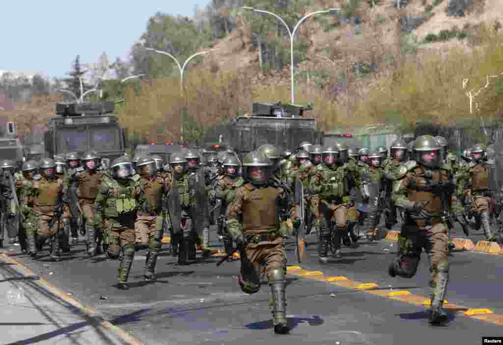 Riot police run toward demonstrators during a march marking the 46th anniversary of the 1973 Chile military coup, in Santiago, Chile, Sept. 8, 2019.