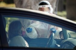 A health care worker at LAC USC Medical Center swabs a person at a drive-through testing center during the coronavirus outbreak, in Los Angeles, California, Dec. 10, 2020.