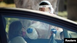 A health care worker at LAC USC Medical Center swabs a person at a drive-through testing center during the coronavirus outbreak, in Los Angeles, California, Dec. 10, 2020. 